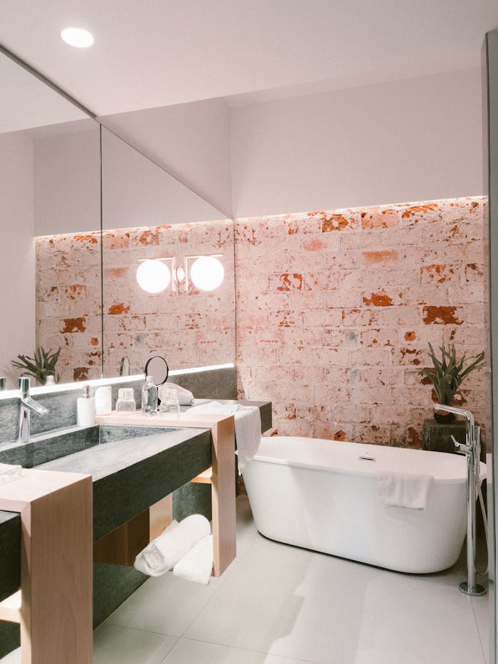 Stylish bathroom featuring a freestanding tub and industrial brick wall.