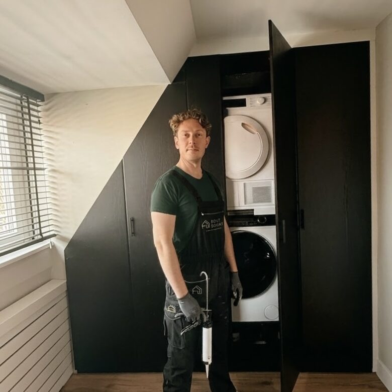 Op maat gemaakte zwarte inbouwkast met geïntegreerde wasmachine en droger tijdens renovatieproject in Haarlem